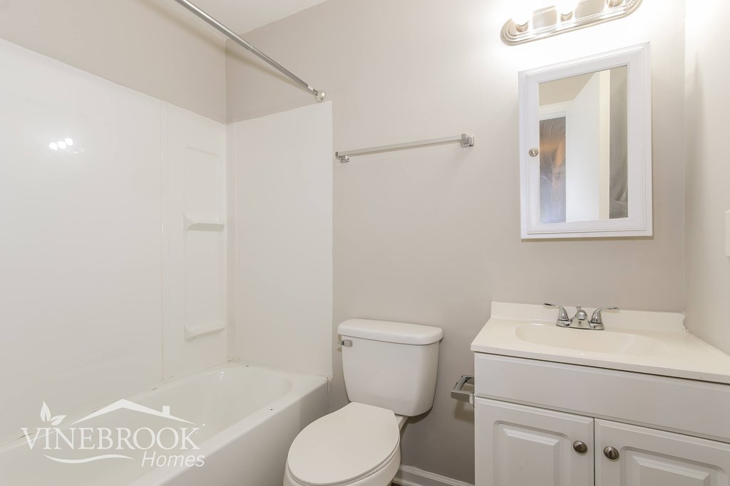 a white bathroom with a tub and a toilet and a sink